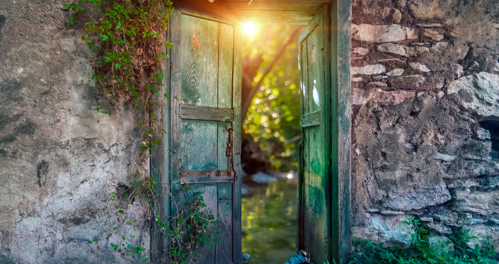 A weather-beaten wooden door in an ancient stone wall covered in ivy, is open slightly to reveal a glimpse of a lush green garden with magical sunlight pouring through